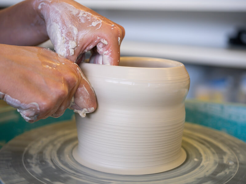 Hands shaping clay on a pottery wheel.